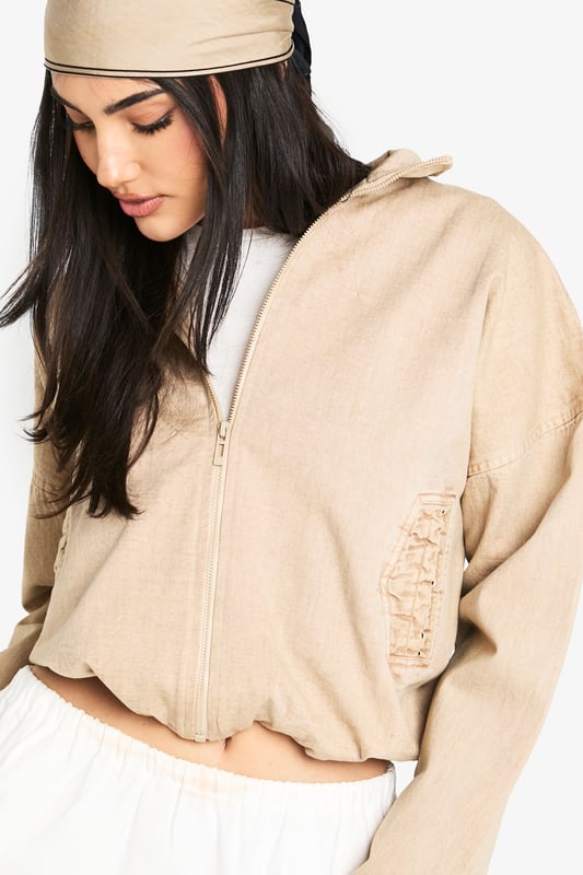 Cropped bomber jacket with a relaxed, oversized fit for effortless styling
        Full front zip closure with ribbed collar, cuffs and hem for a classic bomber silhouette
        Distinctive side pocket detailing with embroidered design elements
        Dropped shoulders and roomy sleeves creating a contemporary, casual shape
        Cotton construction offering breathable comfort for year-round wear
    
    This versatile bomber jacket brings casual cool to your everyday wardrobe. The cropped length pairs beautifully with high-waisted trousers or flowing maxi skirts as shown on our model. For daytime outings, style with a simple white tee, wide-leg trousers and trainers, adding a matching headscarf for a coordinated look. When temperatures drop, layer over a lightweight jumper for added warmth without compromising on style. Perfect for weekend brunches, casual shopping trips or relaxed evening gatherings with friends. The neutral tone makes it an ideal companion piece that works seamlessly with both bold prints and understated basics, allowing you to customise your look for different occasions whilst maintaining that effortlessly chic Boohoo aesthetic.