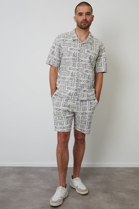 Freshen up your summer wardrobe with this tribal print relaxed fit shirt from Threadbare. This short sleeve printed shirt cut in a relaxed fit is an essential for bringing a bit of style to your outfit. Made from a textured fabric and finished with a revere style collar and button through fastening. Team in the daytime with denim shorts, or smarten up with a pair of chino shorts.