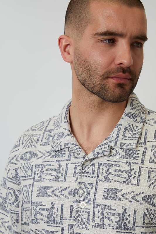 Freshen up your summer wardrobe with this tribal print relaxed fit shirt from Threadbare. This short sleeve printed shirt cut in a relaxed fit is an essential for bringing a bit of style to your outfit. Made from a textured fabric and finished with a revere style collar and button through fastening. Team in the daytime with denim shorts, or smarten up with a pair of chino shorts.