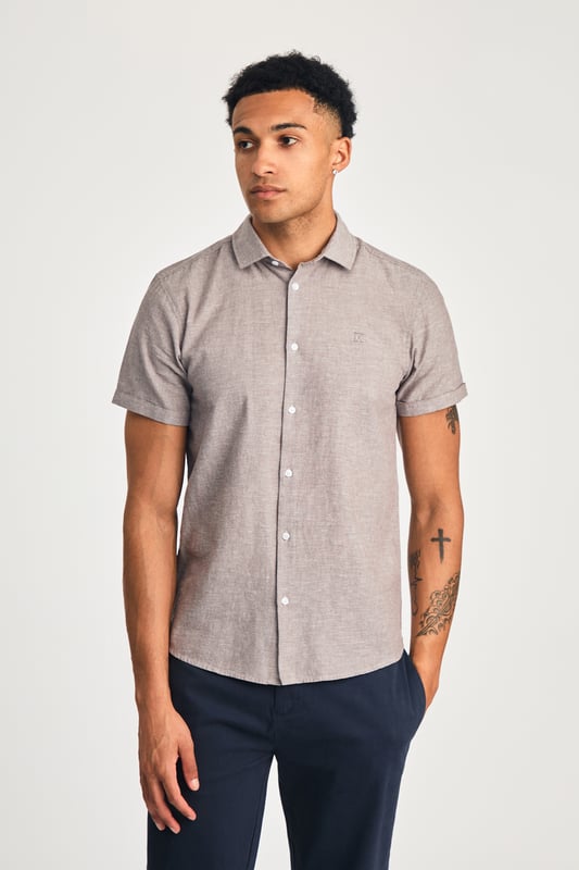 This short sleeve cotton-linen mix shirt by Nines features a sleek embroidered logo on the chest. Lightweight and breathable, it’s perfect for warm days. A stylish and comfortable addition to your wardrobe, offering the ideal balance of relaxed yet refined style.