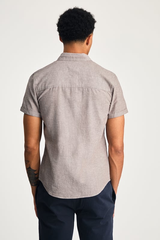 This short sleeve cotton-linen mix shirt by Nines features a sleek embroidered logo on the chest. Lightweight and breathable, it’s perfect for warm days. A stylish and comfortable addition to your wardrobe, offering the ideal balance of relaxed yet refined style.