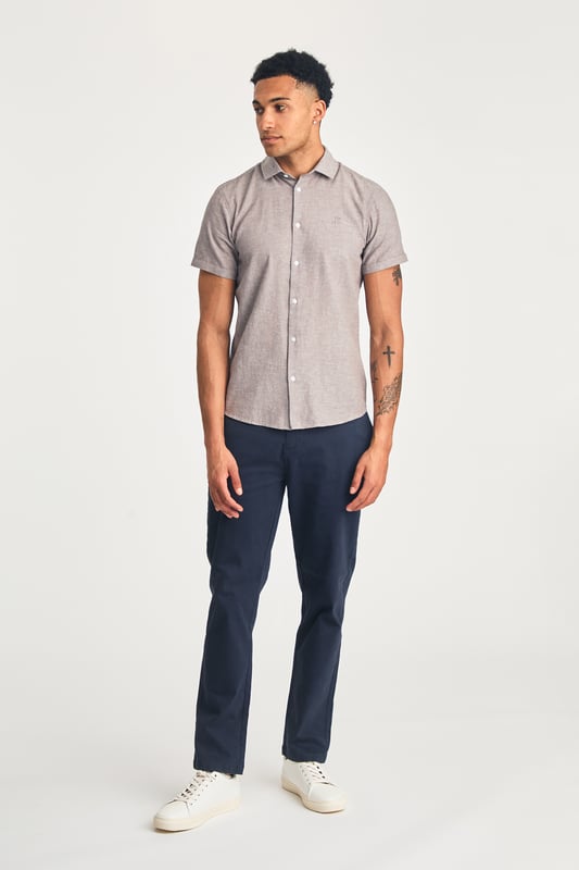 This short sleeve cotton-linen mix shirt by Nines features a sleek embroidered logo on the chest. Lightweight and breathable, it’s perfect for warm days. A stylish and comfortable addition to your wardrobe, offering the ideal balance of relaxed yet refined style.