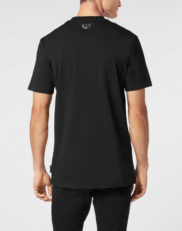 Dit grafische T-shirt is ongegeneerd brutaal en straalt rauwe energie uit met op graffiti geïnspireerd artwork en de kenmerkende kristallen details. Een onverschrokken fusie van kunst, attitude en luxe vakmanschap.    Past het best bij cargos of onder oversized bovenkleding Premium katoenen constructie met een zachte, gestructureerde hand Hand aangebrachte kristallen verheffen de street-art graphic Graffiti-belettering en geweermotief voor maximale visuele impact Een opvallend stuk dat edgy, high-end streetwear definieert