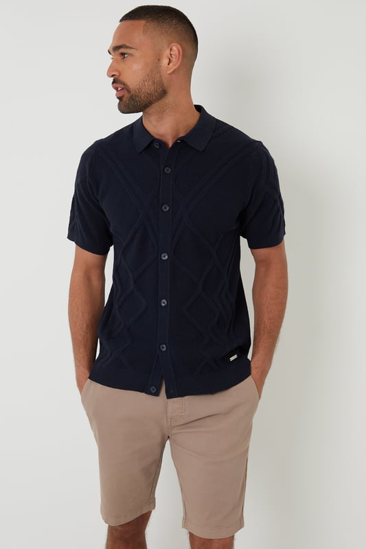 Combine classic style with modern comfort with this knitted polo shirt from Threadbare. With a ribbed placket with button-through fastening, this shirt has a Milano stitch collar and ribbed cuffs and hem. In an all-over textured knit, made from a cotton blend yarn and finished with a metal Threadbare tab above the hem. Pair with chinos or jeans for everyday wear or team with shorts for summer style.