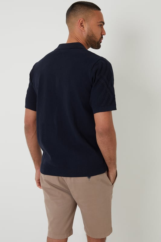 Combine classic style with modern comfort with this knitted polo shirt from Threadbare. With a ribbed placket with button-through fastening, this shirt has a Milano stitch collar and ribbed cuffs and hem. In an all-over textured knit, made from a cotton blend yarn and finished with a metal Threadbare tab above the hem. Pair with chinos or jeans for everyday wear or team with shorts for summer style.