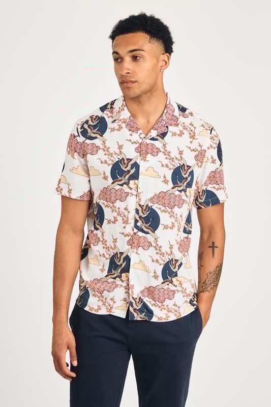 This resort-style shirt by Nines features a cool eagle and blossom print, adding a stylish look to your summer wardrobe. Lightweight and breathable, it's perfect for holidays or sunny days. A standout piece that effortlessly combines comfort and style for a laid-back, eye-catching look.