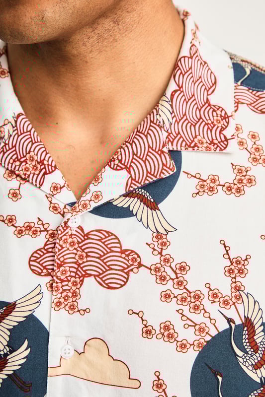 This resort-style shirt by Nines features a cool eagle and blossom print, adding a stylish look to your summer wardrobe. Lightweight and breathable, it's perfect for holidays or sunny days. A standout piece that effortlessly combines comfort and style for a laid-back, eye-catching look.