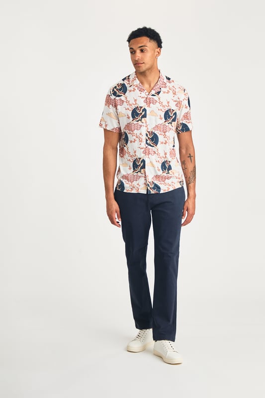 This resort-style shirt by Nines features a cool eagle and blossom print, adding a stylish look to your summer wardrobe. Lightweight and breathable, it's perfect for holidays or sunny days. A standout piece that effortlessly combines comfort and style for a laid-back, eye-catching look.