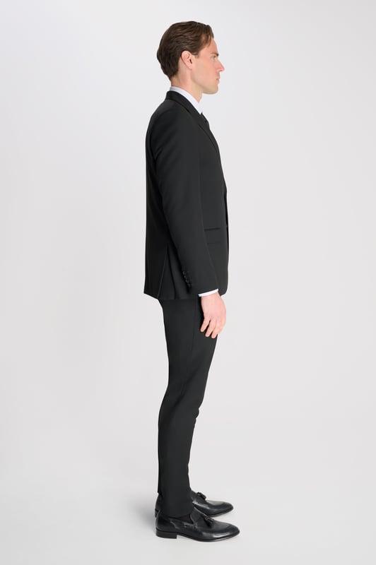 3-Piece Suit Set by Carter & Jones
Elevate your formal wardrobe with the 3-Piece Suit Set by Carter & Jones, designed for the discerning gentleman who values both style and sophistication. This suit set includes a jacket, trousers, and waistcoat, each featuring those classic details that ensure you stand out in any setting.

Jacket: A 2-Button Single Breasted design with a classic cut that exudes modern elegance. The jacket is equipped with two back vents for added comfort and ease of movement. Finished with a distinctive Contrasting Lapel Pin for a touch of personality, the jacket also offers 2 Flap Pockets, a chest pocket, and multiple internal pockets for practicality. Fully lined for a premium finish.

Trousers: Pleated trousers that offer a refined silhouette with a Hook and Bar Closure, combining comfort with style for an impeccable fit.

Waistcoat: A statement piece, featuring a Cinch Belt for a tailored fit, Silken Lining, and a Button Closure for that perfect polished look.

Slim Fit 

Main Fabric 68% Polyester 29% Viscose 3% Elastane.

Lining 100% Polyester.

Dry Clean Only.

This suit comes nested, meaning the trousers will have a 6 inch difference to the jacket (eg.: Jacket & Waistcoat - 38R | Trousers - 32R).

This 3-piece suit set is the ideal choice for weddings, business events, or any occasion that requires a sharp, sophisticated appearance. Carter & Jones delivers exceptional craftsmanship, ensuring you look your best with every wear.