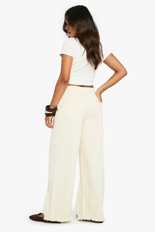 Wide leg silhouette for a relaxed, on-trend fit
        Distinctive frayed hem detail adding textural interest
        100% cotton denim for breathable comfort
        Classic five-pocket design for practicality
        High-rise waist perfect for tucking in tops
    
    These Petite Ecru Jeans from Boohoo showcase contemporary casual style with their wide leg cut and characterful frayed hem. The relaxed silhouette offers both comfort and fashion-forward appeal, whilst the high-rise waist creates a flattering line. Style them as seen with a cropped white top and oversized shirt for an effortlessly cool daytime look, or dress them up with a fitted bodysuit and chunky jewellery for evening socials. The neutral tone makes these jeans incredibly versatile - pair with brown accessories as shown for a harmonious aesthetic, or contrast with bold colours to make a statement. Perfect for weekend brunches, shopping trips or casual meet-ups with friends, these jeans offer the ideal balance of comfort and style for the fashion-conscious woman who values both trend and wearability.