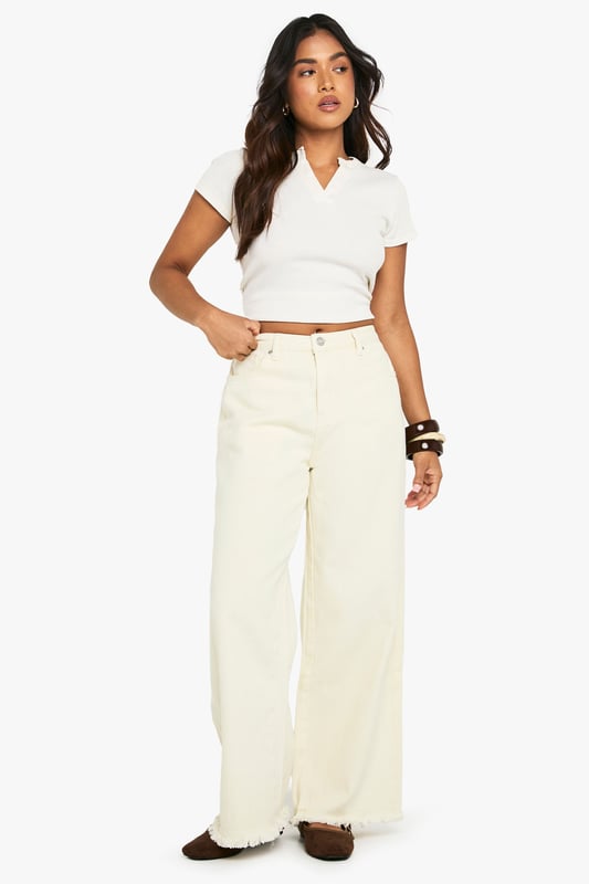 Wide leg silhouette for a relaxed, on-trend fit
        Distinctive frayed hem detail adding textural interest
        100% cotton denim for breathable comfort
        Classic five-pocket design for practicality
        High-rise waist perfect for tucking in tops
    
    These Petite Ecru Jeans from Boohoo showcase contemporary casual style with their wide leg cut and characterful frayed hem. The relaxed silhouette offers both comfort and fashion-forward appeal, whilst the high-rise waist creates a flattering line. Style them as seen with a cropped white top and oversized shirt for an effortlessly cool daytime look, or dress them up with a fitted bodysuit and chunky jewellery for evening socials. The neutral tone makes these jeans incredibly versatile - pair with brown accessories as shown for a harmonious aesthetic, or contrast with bold colours to make a statement. Perfect for weekend brunches, shopping trips or casual meet-ups with friends, these jeans offer the ideal balance of comfort and style for the fashion-conscious woman who values both trend and wearability.
