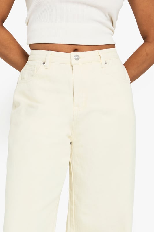 Wide leg silhouette for a relaxed, on-trend fit
        Distinctive frayed hem detail adding textural interest
        100% cotton denim for breathable comfort
        Classic five-pocket design for practicality
        High-rise waist perfect for tucking in tops
    
    These Petite Ecru Jeans from Boohoo showcase contemporary casual style with their wide leg cut and characterful frayed hem. The relaxed silhouette offers both comfort and fashion-forward appeal, whilst the high-rise waist creates a flattering line. Style them as seen with a cropped white top and oversized shirt for an effortlessly cool daytime look, or dress them up with a fitted bodysuit and chunky jewellery for evening socials. The neutral tone makes these jeans incredibly versatile - pair with brown accessories as shown for a harmonious aesthetic, or contrast with bold colours to make a statement. Perfect for weekend brunches, shopping trips or casual meet-ups with friends, these jeans offer the ideal balance of comfort and style for the fashion-conscious woman who values both trend and wearability.