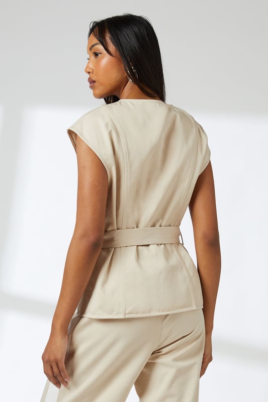 Elegant button-front waistcoat with distinctive round buttons for a refined finish
        Flattering cap sleeves that create a clean, contemporary silhouette
        Self-tie belt that cinches the waist for a customised fit
        Collarless neckline offering a modern, minimalist aesthetic
        Regular fit design ensuring comfortable all-day wear
    
    This versatile Principles waistcoat brings sophisticated structure to your daywear collection. The clean lines and button detailing create a polished look that works beautifully for various casual occasions. Style it as shown with matching wide-leg trousers for an effortlessly coordinated ensemble, or break it up with slim-fit denim and trainers for a more relaxed approach. The adjustable belt allows you to create definition at the waist, making it flattering for all body types. Perfect for family gatherings, brunch dates or gallery visits, this piece transitions seamlessly from day to evening when paired with statement jewellery and sleek mules. The breathable lyocell-cotton blend ensures comfort throughout the day, while the timeless design promises to remain a wardrobe staple for seasons to come.