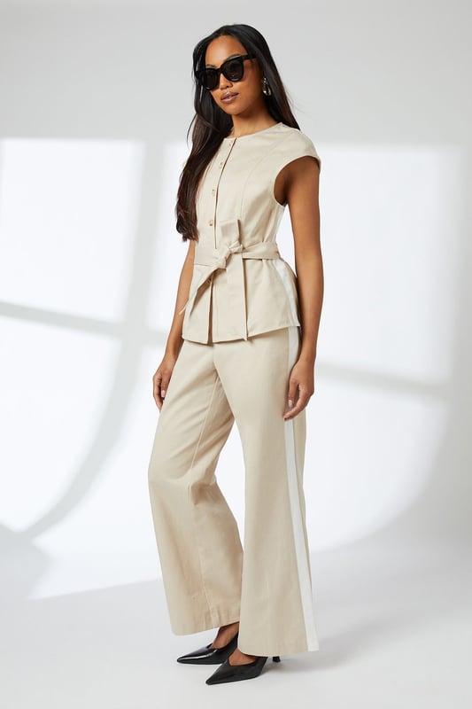 Elegant button-front waistcoat with distinctive round buttons for a refined finish
        Flattering cap sleeves that create a clean, contemporary silhouette
        Self-tie belt that cinches the waist for a customised fit
        Collarless neckline offering a modern, minimalist aesthetic
        Regular fit design ensuring comfortable all-day wear
    
    This versatile Principles waistcoat brings sophisticated structure to your daywear collection. The clean lines and button detailing create a polished look that works beautifully for various casual occasions. Style it as shown with matching wide-leg trousers for an effortlessly coordinated ensemble, or break it up with slim-fit denim and trainers for a more relaxed approach. The adjustable belt allows you to create definition at the waist, making it flattering for all body types. Perfect for family gatherings, brunch dates or gallery visits, this piece transitions seamlessly from day to evening when paired with statement jewellery and sleek mules. The breathable lyocell-cotton blend ensures comfort throughout the day, while the timeless design promises to remain a wardrobe staple for seasons to come.