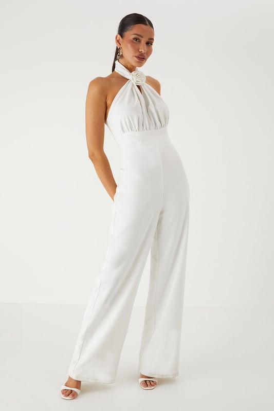 Striking halterneck design with elegant corsage detail for a dramatic neckline statement
        Structured corset bodice that creates a flattering silhouette
        Wide leg cut offering sophisticated movement and comfort
        Backless design for a show-stopping rear view
        Floor-length style perfect for formal occasions and evening events
    
    Command attention in this stunning MissPap halterneck jumpsuit that combines contemporary style with classic elegance. The corsage detail at the neckline creates a beautiful focal point, whilst the structured corset bodice sculpts and defines your figure. The flowing wide legs offer a graceful silhouette that moves beautifully as you walk. Style with statement earrings as seen on our model and strappy heels for a sophisticated ensemble perfect for weddings, graduation ceremonies or summer garden parties. For cooler evenings, drape a lightweight shawl over your shoulders to maintain the elegant aesthetic. This versatile piece transitions effortlessly from daytime formality to evening glamour, making it an essential addition to your occasion wardrobe.