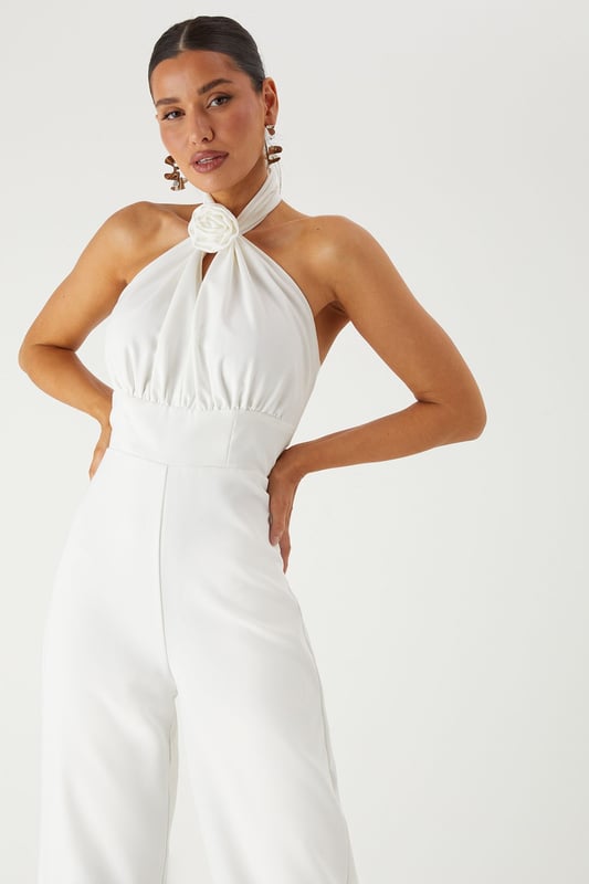 Striking halterneck design with elegant corsage detail for a dramatic neckline statement
        Structured corset bodice that creates a flattering silhouette
        Wide leg cut offering sophisticated movement and comfort
        Backless design for a show-stopping rear view
        Floor-length style perfect for formal occasions and evening events
    
    Command attention in this stunning MissPap halterneck jumpsuit that combines contemporary style with classic elegance. The corsage detail at the neckline creates a beautiful focal point, whilst the structured corset bodice sculpts and defines your figure. The flowing wide legs offer a graceful silhouette that moves beautifully as you walk. Style with statement earrings as seen on our model and strappy heels for a sophisticated ensemble perfect for weddings, graduation ceremonies or summer garden parties. For cooler evenings, drape a lightweight shawl over your shoulders to maintain the elegant aesthetic. This versatile piece transitions effortlessly from daytime formality to evening glamour, making it an essential addition to your occasion wardrobe.