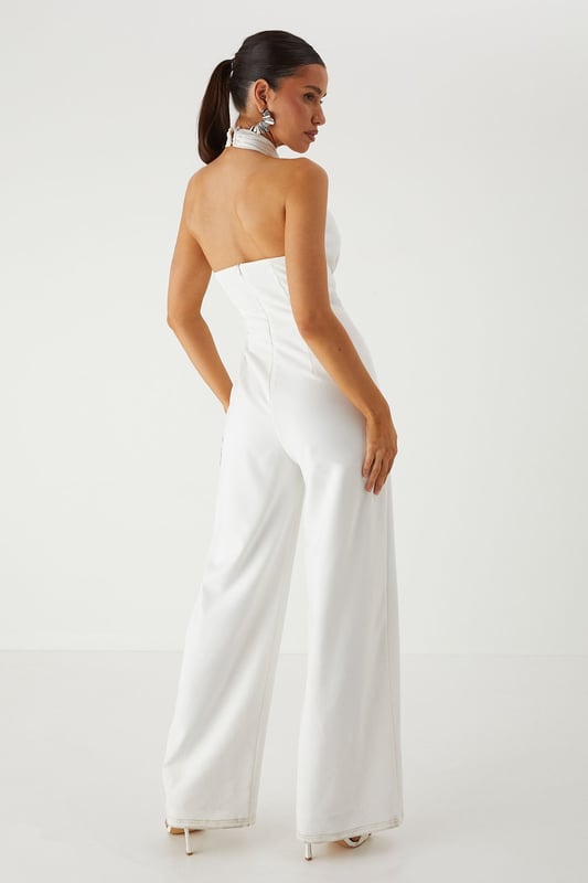 Striking halterneck design with elegant corsage detail for a dramatic neckline statement
        Structured corset bodice that creates a flattering silhouette
        Wide leg cut offering sophisticated movement and comfort
        Backless design for a show-stopping rear view
        Floor-length style perfect for formal occasions and evening events
    
    Command attention in this stunning MissPap halterneck jumpsuit that combines contemporary style with classic elegance. The corsage detail at the neckline creates a beautiful focal point, whilst the structured corset bodice sculpts and defines your figure. The flowing wide legs offer a graceful silhouette that moves beautifully as you walk. Style with statement earrings as seen on our model and strappy heels for a sophisticated ensemble perfect for weddings, graduation ceremonies or summer garden parties. For cooler evenings, drape a lightweight shawl over your shoulders to maintain the elegant aesthetic. This versatile piece transitions effortlessly from daytime formality to evening glamour, making it an essential addition to your occasion wardrobe.