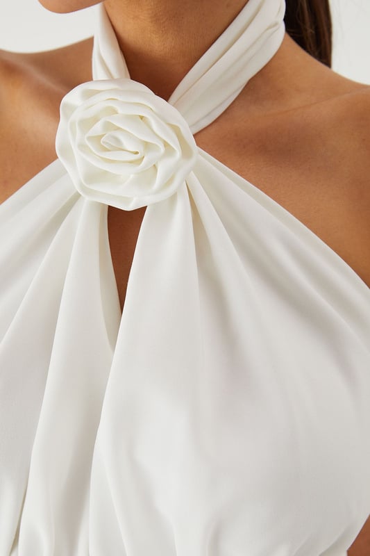 Striking halterneck design with elegant corsage detail for a dramatic neckline statement
        Structured corset bodice that creates a flattering silhouette
        Wide leg cut offering sophisticated movement and comfort
        Backless design for a show-stopping rear view
        Floor-length style perfect for formal occasions and evening events
    
    Command attention in this stunning MissPap halterneck jumpsuit that combines contemporary style with classic elegance. The corsage detail at the neckline creates a beautiful focal point, whilst the structured corset bodice sculpts and defines your figure. The flowing wide legs offer a graceful silhouette that moves beautifully as you walk. Style with statement earrings as seen on our model and strappy heels for a sophisticated ensemble perfect for weddings, graduation ceremonies or summer garden parties. For cooler evenings, drape a lightweight shawl over your shoulders to maintain the elegant aesthetic. This versatile piece transitions effortlessly from daytime formality to evening glamour, making it an essential addition to your occasion wardrobe.