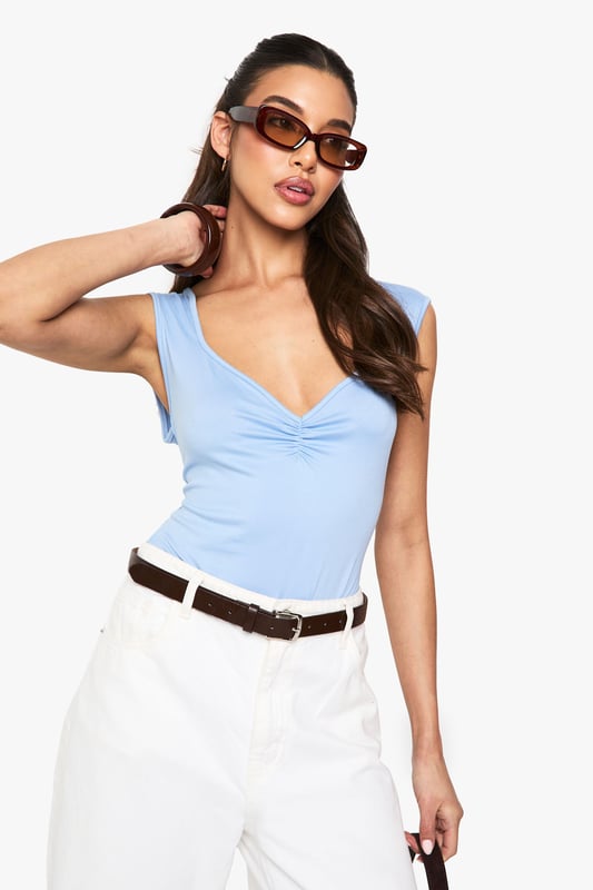 Soft touch bodysuit with elegant ruched bust detail
        Flattering sweetheart neckline for a feminine silhouette
        Sleeveless design perfect for layering or wearing alone
        Figure-hugging fit with stretch for all-day comfort
        Versatile piece that transitions effortlessly from day to night
    
    This ultra-soft bodysuit combines comfort with chic styling, making it a wardrobe essential for the fashion-forward woman. The ruched bust detail and sweetheart neckline create a flattering shape that complements all figures. Style with high-waisted white trousers and a slim belt for a polished daytime look, as shown on our model. For evening occasions, swap the casual accessories for statement jewellery and a structured blazer. The sleek design tucks in perfectly without bunching, creating a seamless silhouette that works brilliantly under both tailored and relaxed pieces. Perfect for casual gatherings or dressed up for drinks with the girls, this bodysuit offers endless styling possibilities throughout the seasons.