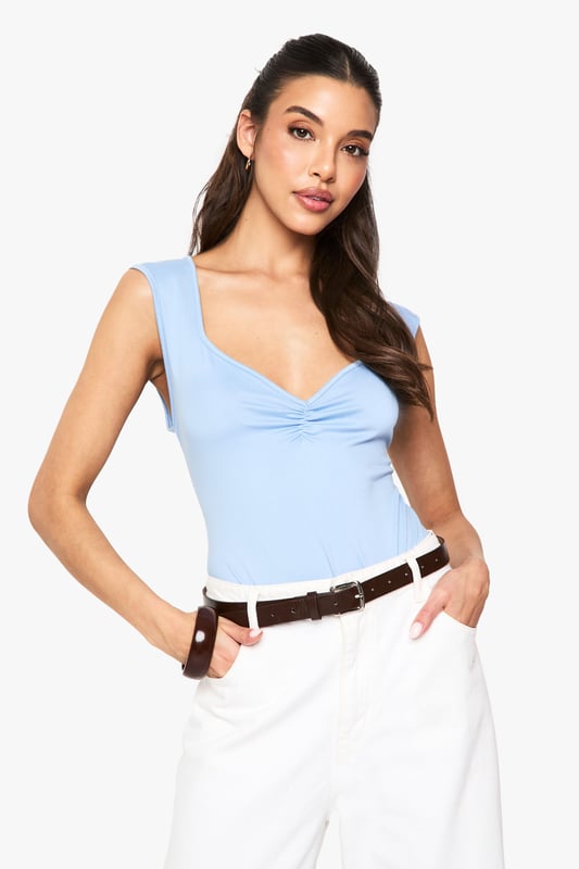 Soft touch bodysuit with elegant ruched bust detail
        Flattering sweetheart neckline for a feminine silhouette
        Sleeveless design perfect for layering or wearing alone
        Figure-hugging fit with stretch for all-day comfort
        Versatile piece that transitions effortlessly from day to night
    
    This ultra-soft bodysuit combines comfort with chic styling, making it a wardrobe essential for the fashion-forward woman. The ruched bust detail and sweetheart neckline create a flattering shape that complements all figures. Style with high-waisted white trousers and a slim belt for a polished daytime look, as shown on our model. For evening occasions, swap the casual accessories for statement jewellery and a structured blazer. The sleek design tucks in perfectly without bunching, creating a seamless silhouette that works brilliantly under both tailored and relaxed pieces. Perfect for casual gatherings or dressed up for drinks with the girls, this bodysuit offers endless styling possibilities throughout the seasons.