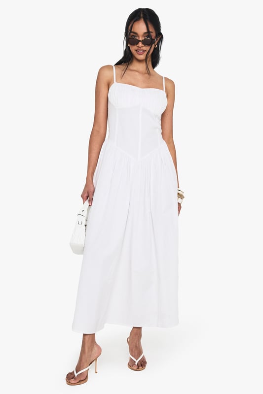 Crafted from breathable cotton poplin for all-day comfort
        Flattering milkmaid design with structured bodice and flowing maxi skirt
        Elegant sweetheart neckline to showcase your dcolletage
        Delicate adjustable shoulder straps for the perfect fit
        Ankle-grazing maxi length ideal for warm-weather styling
    
    This cotton milkmaid maxi dress captures effortless summer style with its classic silhouette and breezy appeal. The structured bodice creates a flattering shape while the sweetheart neckline adds a touch of feminine charm. Perfect for casual daytime events, style with flat sandals and a mini handbag as shown for a relaxed brunch with friends or family gatherings. For cooler evenings, layer with a lightweight denim jacket and accessorise with bangles for added interest. The versatile design transitions beautifully from garden parties to beachside strolls, making it a wardrobe essential for the warmer months. The cotton fabric ensures breathability whilst the maxi length offers a graceful movement that complements any casual occasion.