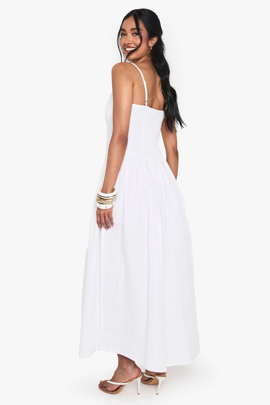 Crafted from breathable cotton poplin for all-day comfort
        Flattering milkmaid design with structured bodice and flowing maxi skirt
        Elegant sweetheart neckline to showcase your dcolletage
        Delicate adjustable shoulder straps for the perfect fit
        Ankle-grazing maxi length ideal for warm-weather styling
    
    This cotton milkmaid maxi dress captures effortless summer style with its classic silhouette and breezy appeal. The structured bodice creates a flattering shape while the sweetheart neckline adds a touch of feminine charm. Perfect for casual daytime events, style with flat sandals and a mini handbag as shown for a relaxed brunch with friends or family gatherings. For cooler evenings, layer with a lightweight denim jacket and accessorise with bangles for added interest. The versatile design transitions beautifully from garden parties to beachside strolls, making it a wardrobe essential for the warmer months. The cotton fabric ensures breathability whilst the maxi length offers a graceful movement that complements any casual occasion.