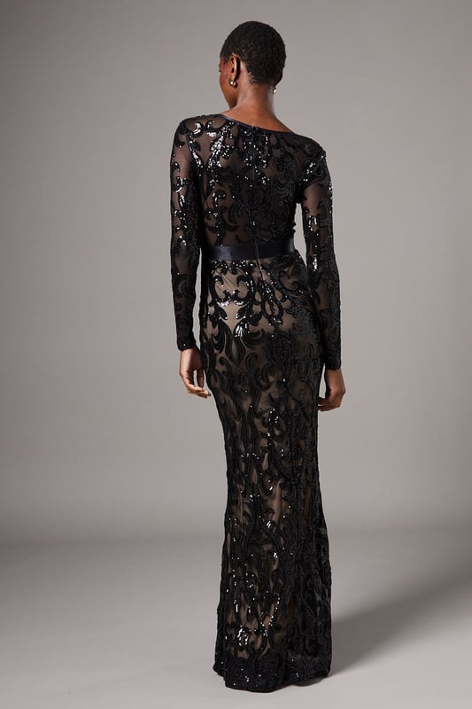 Striking sequin embellishment across intricate pattern detailing
        Elegant V-neckline frames the dcolletage beautifully
        Figure-enhancing maxi silhouette with floor-sweeping length
        Long sleeves offer sophisticated coverage for formal occasions
        Semi-sheer overlay creates a captivating contrast against the lining
    
    Make an unforgettable entrance in this show-stopping sequin maxi dress from Coast. The alluring V-neckline and body-contouring fit create a silhouette that commands attention, whilst the intricate pattern detailing adds depth and dimension to your look. Perfect for black-tie events, evening galas or wedding receptions, this dress requires minimal accessorising-simply pair with delicate drop earrings and a sleek clutch as seen on our model. The floor-length design creates a graceful sweep as you move, whilst the long sleeves provide an elegant balance to the striking neckline. Style with strappy heeled sandals and a tailored evening coat for cooler evenings. This dress transitions effortlessly from formal ceremonies to evening celebrations, ensuring you remain the epitome of sophistication throughout any special occasion.