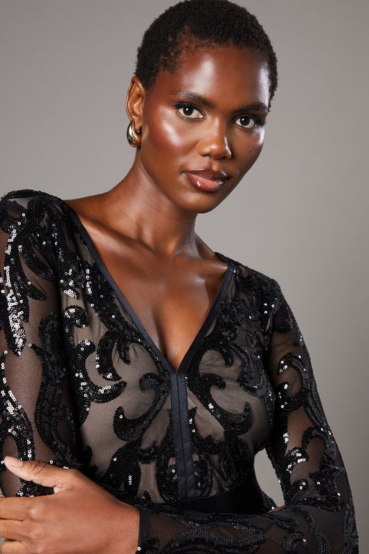 Striking sequin embellishment across intricate pattern detailing
        Elegant V-neckline frames the dcolletage beautifully
        Figure-enhancing maxi silhouette with floor-sweeping length
        Long sleeves offer sophisticated coverage for formal occasions
        Semi-sheer overlay creates a captivating contrast against the lining
    
    Make an unforgettable entrance in this show-stopping sequin maxi dress from Coast. The alluring V-neckline and body-contouring fit create a silhouette that commands attention, whilst the intricate pattern detailing adds depth and dimension to your look. Perfect for black-tie events, evening galas or wedding receptions, this dress requires minimal accessorising-simply pair with delicate drop earrings and a sleek clutch as seen on our model. The floor-length design creates a graceful sweep as you move, whilst the long sleeves provide an elegant balance to the striking neckline. Style with strappy heeled sandals and a tailored evening coat for cooler evenings. This dress transitions effortlessly from formal ceremonies to evening celebrations, ensuring you remain the epitome of sophistication throughout any special occasion.