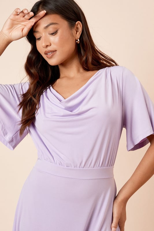 Elegant cowl neckline creates a soft, draped effect at the front
        Flutter sleeves add a feminine touch and gentle movement
        Flattering midi length falls elegantly below the knee
        Tie-back detail creates a customised fit and adds visual interest
        Defined waistline creates a figure-enhancing silhouette
    
    This Dorothy Perkins midi dress combines comfort with sophistication through its graceful cowl neckline and flowing silhouette. The delicate flutter sleeves provide just the right amount of coverage whilst maintaining a light, airy feel. The tie-back detail allows for a personalised fit that accentuates your waistline beautifully. Style with simple strappy sandals and minimal jewellery for casual brunches with the girls, or dress it up with block-heeled ankle boots and a structured crossbody bag for family gatherings. The versatile design makes it perfect for baby showers or afternoon tea, where you can pair it with a lightweight cardigan and ballet flats for a polished yet comfortable ensemble. This dress transitions effortlessly from daytime casual to evening drinks with a simple change of accessories.