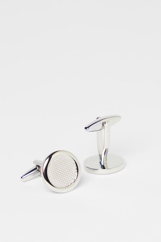 Elegant round design with textured detailing for a sophisticated finish
        Secure toggle fastening ensures cufflinks stay in place throughout the day
        Polished silver-tone metal creates a versatile accessory for formal attire
        Subtle textured pattern adds distinctive character without being overstated
        Classic Burton craftsmanship that complements any formal shirt
    
    These detailed cufflinks offer the perfect finishing touch to your formal ensemble. The textured circular design presents a refined aesthetic that works brilliantly with crisp white shirts or adds character to coloured options. Ideal for important meetings, weddings, or sophisticated evening events, they provide just the right amount of polish without appearing ostentatious. Pair with a tailored Burton suit for a coordinated look, or use them to sharpen up a smart casual outfit when you want to make an impression. The timeless design ensures these cufflinks will remain a staple in your accessories collection, offering versatility across various occasions where you need to present a distinguished appearance. Their understated elegance makes them suitable for everything from job interviews to anniversary dinners.