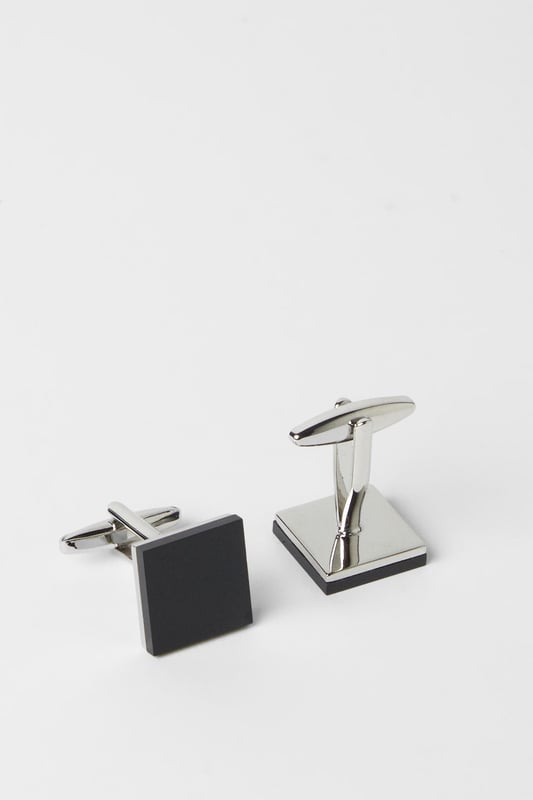 Classic square design with contrasting black face and polished silver trim
        Secure T-bar fastening for reliable wear throughout formal occasions
        Versatile size that complements both standard and French cuffs
        Sleek metal construction offering durability and a refined finish
        Burton London signature quality, perfect for adding subtle sophistication to any formal ensemble
    
    These timeless black and silver cufflinks present the perfect finishing touch for your formal attire. The understated square design offers versatility that complements a range of shirt styles and suit colours, making them an essential addition to your accessories collection. Pair with a crisp white shirt and tailored Burton suit for important business meetings or special occasions where attention to detail matters. The contrasting elements create visual interest without overwhelming your overall look - ideal for the gentleman who appreciates classic style with contemporary appeal. These cufflinks transition effortlessly from daytime professional settings to evening functions, ensuring you're always appropriately dressed for the occasion. A smart investment piece that will serve your wardrobe for years to come, reflecting a considered approach to formal dressing that never goes out of fashion.
