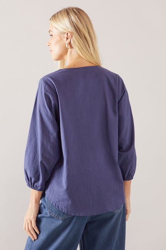 Elegant V-neckline with delicate ruffle trim detailing
        Relaxed overhead design for effortless styling
        Soft cotton fabric ensures all-day comfort
        Versatile three-quarter length balloon sleeves
        Flattering petite fit, perfect for smaller frames
    
    This charming Wallis ruffle overhead shirt combines sophisticated style with everyday comfort. The delicate ruffle trim along the V-neckline adds a feminine touch to this versatile piece, while the relaxed silhouette ensures a flattering fit for various body types. Style it as shown with wide-leg denim and trainers for casual weekend brunches, or tuck it into tailored trousers with ballet flats for family gatherings. The lightweight cotton construction makes it ideal for layering under cardigans during cooler months or wearing alone during warmer days. Perfect for daytime occasions when you want to look polished yet comfortable, this shirt will quickly become a wardrobe staple that transitions seamlessly from shopping trips to casual lunch dates with friends.