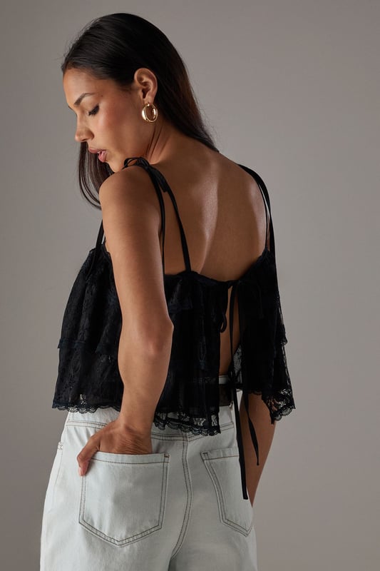 Delicate lace overlay with intricate bohemian-inspired pattern
        Adjustable tie straps for a customised fit
        Cropped length perfect for high-waisted styling
        Tiered design creating a relaxed, floaty silhouette
        Subtle front tie detail adding feminine charm
    
    This Warehouse Bohemian Lace Cami Top brings effortless style to your casual wardrobe. The delicate lace construction creates a light, airy feel while the cropped silhouette pairs beautifully with high-waisted bottoms. Style with light-wash denim shorts and western boots for a festival-ready look, or team with wide-leg trousers and trainers for weekend brunches. The adjustable straps ensure comfort throughout the day, while the tiered design adds movement and dimension. Perfect for summer gatherings, garden parties or holiday evenings, this versatile piece can be dressed down with a denim jacket or styled with statement jewellery for more special occasions. Machine washable for easy care, this top combines practicality with Warehouse's signature confident, feminine aesthetic.