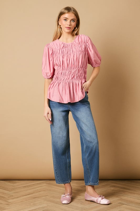 Beautifully textured shirred bodice creates a flattering silhouette
        Charming puff sleeves add a feminine touch to this daywear essential
        Crew neckline offers a classic, versatile finish
        Gathered waist detail creates definition and shape
        Regular fit ensures comfort for all-day wear
    
    This delightful Shirred Bodice Puff Sleeve Top from Oasis brings a touch of romance to your everyday wardrobe. The intricate shirring detail across the bodice creates beautiful texture whilst the puff sleeves add a playful, feminine element that's quintessentially Oasis. Style with relaxed denim jeans and ballet flats for a casual weekend brunch, or pair with tailored trousers and loafers for a smart-casual office look. The versatile crew neckline works beautifully with delicate necklaces or statement earrings. Perfect for family gatherings or casual coffee dates, this top can be layered under a denim jacket when the temperature drops. The gathered waist creates a flattering shape that works wonderfully with both fitted and looser bottoms, making this a truly adaptable piece for your daywear collection.