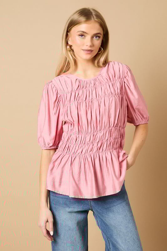 Beautifully textured shirred bodice creates a flattering silhouette
        Charming puff sleeves add a feminine touch to this daywear essential
        Crew neckline offers a classic, versatile finish
        Gathered waist detail creates definition and shape
        Regular fit ensures comfort for all-day wear
    
    This delightful Shirred Bodice Puff Sleeve Top from Oasis brings a touch of romance to your everyday wardrobe. The intricate shirring detail across the bodice creates beautiful texture whilst the puff sleeves add a playful, feminine element that's quintessentially Oasis. Style with relaxed denim jeans and ballet flats for a casual weekend brunch, or pair with tailored trousers and loafers for a smart-casual office look. The versatile crew neckline works beautifully with delicate necklaces or statement earrings. Perfect for family gatherings or casual coffee dates, this top can be layered under a denim jacket when the temperature drops. The gathered waist creates a flattering shape that works wonderfully with both fitted and looser bottoms, making this a truly adaptable piece for your daywear collection.
