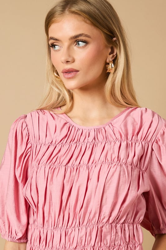 Beautifully textured shirred bodice creates a flattering silhouette
        Charming puff sleeves add a feminine touch to this daywear essential
        Crew neckline offers a classic, versatile finish
        Gathered waist detail creates definition and shape
        Regular fit ensures comfort for all-day wear
    
    This delightful Shirred Bodice Puff Sleeve Top from Oasis brings a touch of romance to your everyday wardrobe. The intricate shirring detail across the bodice creates beautiful texture whilst the puff sleeves add a playful, feminine element that's quintessentially Oasis. Style with relaxed denim jeans and ballet flats for a casual weekend brunch, or pair with tailored trousers and loafers for a smart-casual office look. The versatile crew neckline works beautifully with delicate necklaces or statement earrings. Perfect for family gatherings or casual coffee dates, this top can be layered under a denim jacket when the temperature drops. The gathered waist creates a flattering shape that works wonderfully with both fitted and looser bottoms, making this a truly adaptable piece for your daywear collection.