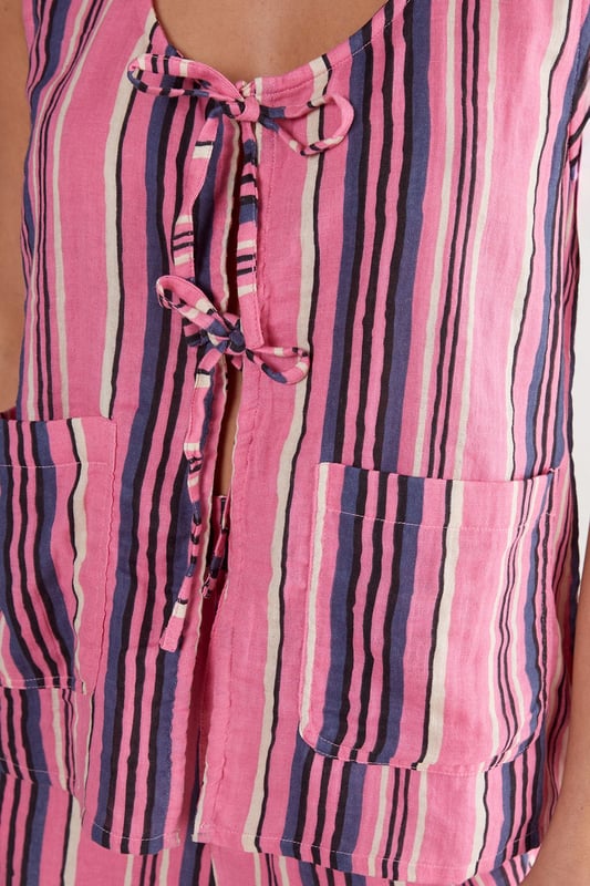 Sleeveless vest with eye-catching vertical stripe pattern
        Distinctive tie-front detail with multiple closures for adjustable styling
        Scoop neckline offering a flattering silhouette
        Practical dual front pockets for convenience
        Relaxed fit with slightly longer back hem for versatile coverage
    
    This striking Nasty Gal vest brings playful charm to your casual wardrobe. The tie-front design creates a customisable fit that works beautifully whether worn loose or secured for a more defined shape. Style with the matching striped trousers as seen on our model for a coordinated set that makes a statement, or break it up with your favourite denim shorts for a more relaxed approach. The lightweight cotton fabric makes this piece perfect for warm-weather gatherings, weekend brunches or casual garden parties. Layer under a denim jacket when temperatures drop, or throw on with trainers for an effortlessly cool daytime look. The versatile design transitions seamlessly from beach cover-up to family barbecue attire, making it an essential addition to your summer capsule wardrobe.