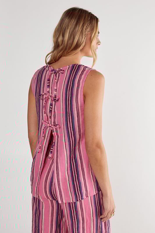 Sleeveless vest with eye-catching vertical stripe pattern
        Distinctive tie-front detail with multiple closures for adjustable styling
        Scoop neckline offering a flattering silhouette
        Practical dual front pockets for convenience
        Relaxed fit with slightly longer back hem for versatile coverage
    
    This striking Nasty Gal vest brings playful charm to your casual wardrobe. The tie-front design creates a customisable fit that works beautifully whether worn loose or secured for a more defined shape. Style with the matching striped trousers as seen on our model for a coordinated set that makes a statement, or break it up with your favourite denim shorts for a more relaxed approach. The lightweight cotton fabric makes this piece perfect for warm-weather gatherings, weekend brunches or casual garden parties. Layer under a denim jacket when temperatures drop, or throw on with trainers for an effortlessly cool daytime look. The versatile design transitions seamlessly from beach cover-up to family barbecue attire, making it an essential addition to your summer capsule wardrobe.