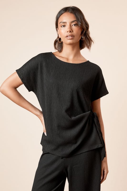 Elegant jersey t-shirt featuring a distinctive side knot detail that creates a flattering silhouette
        Classic crew neckline offers versatile styling options for both daytime and evening looks
        Short sleeves with a relaxed fit provide comfortable movement throughout the day
        Soft, textured jersey fabric with slight stretch ensures all-day comfort and shape retention
        Side tie detail adds a contemporary twist to this wardrobe essential
    
    This Dorothy Perkins knot tie side t-shirt effortlessly blends comfort with sophistication. The thoughtful side tie detail creates gentle gathering that flatters your figure whilst adding visual interest to an otherwise simple silhouette. Perfect for casual brunches with friends, pair with wide-leg trousers and sandals as shown for an effortlessly chic daytime ensemble. For family gatherings, style with your favourite denim and ballet flats for a polished yet relaxed look. The versatile crew neckline works beautifully with delicate jewellery for those occasions when you want to appear put-together without trying too hard. The textured jersey fabric drapes beautifully and maintains its shape throughout the day, making this top a reliable choice for your busy lifestyle. A true wardrobe staple that transitions seamlessly from casual coffee dates to baby showers with just a change of accessories.