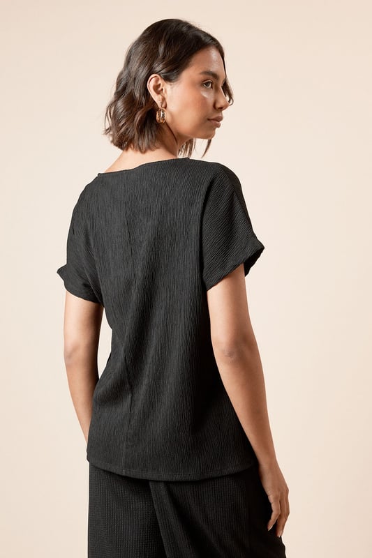 Elegant jersey t-shirt featuring a distinctive side knot detail that creates a flattering silhouette
        Classic crew neckline offers versatile styling options for both daytime and evening looks
        Short sleeves with a relaxed fit provide comfortable movement throughout the day
        Soft, textured jersey fabric with slight stretch ensures all-day comfort and shape retention
        Side tie detail adds a contemporary twist to this wardrobe essential
    
    This Dorothy Perkins knot tie side t-shirt effortlessly blends comfort with sophistication. The thoughtful side tie detail creates gentle gathering that flatters your figure whilst adding visual interest to an otherwise simple silhouette. Perfect for casual brunches with friends, pair with wide-leg trousers and sandals as shown for an effortlessly chic daytime ensemble. For family gatherings, style with your favourite denim and ballet flats for a polished yet relaxed look. The versatile crew neckline works beautifully with delicate jewellery for those occasions when you want to appear put-together without trying too hard. The textured jersey fabric drapes beautifully and maintains its shape throughout the day, making this top a reliable choice for your busy lifestyle. A true wardrobe staple that transitions seamlessly from casual coffee dates to baby showers with just a change of accessories.
