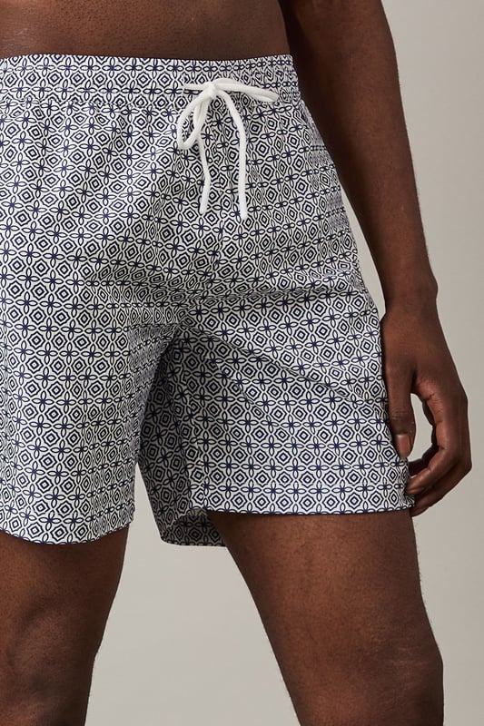 Classic mid-length swim shorts with all-over geometric print
        Comfortable adjustable drawstring waist for the perfect fit
        Quick-drying woven fabric ideal for beach and poolside wear
        Side pockets for convenient storage of small essentials
        Relaxed fit design offering ease of movement during activities
    
    These Burton swim shorts combine practicality with understated style for the modern man who values both comfort and classic design. The distinctive geometric print adds visual interest without being overly bold, making these shorts versatile enough for various summer settings. Pair with a plain white t-shirt and casual shirt as shown for a relaxed beachside lunch, or simply throw on with your favourite sunglasses and flip-flops for a day by the pool. The adjustable waist ensures all-day comfort whether you're swimming, playing beach volleyball, or enjoying a casual barbecue with mates. These shorts transition effortlessly from daytime water activities to evening drinks at a beachfront bar, making them an essential addition to your holiday wardrobe and weekend outings throughout the summer months.