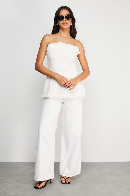 Strapless bandeau design with distinctive frayed edge detailing along the top and bottom hems
        Structured cotton denim fabric provides excellent shape retention and support
        Flattering A-line silhouette that gently flares from the bust to create a feminine profile
        Versatile length that works perfectly as a standalone top or layered piece
        Visible seam detailing adds architectural interest and enhances the contemporary aesthetic
    
    This Warehouse denim bandeau top brings effortless edge to your daywear collection. The raw, frayed edges create a deliberately undone finish that contrasts beautifully with the structured silhouette. Style with the matching frayed denim trousers for a coordinated set that makes a statement, or break it up with your favourite high-waisted jeans for a double denim moment. For casual outings, pair with trainers and oversized gold hoops for an ensemble that transitions seamlessly from weekend brunches to afternoon shopping trips. The cotton fabric offers breathable comfort whilst maintaining its shape throughout the day. This piece embodies Warehouse's confident, feminine aesthetic - perfect for the fashion-forward woman who appreciates contemporary design with a touch of attitude.