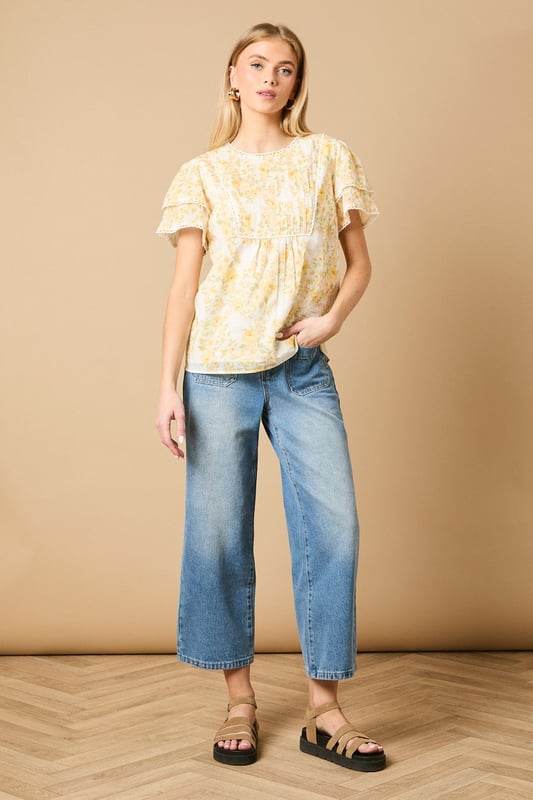 Charming crew neck blouse with delicate frill shoulder detail for a feminine touch
        Elegant pintuck detailing on the front bodice creates subtle texture and visual interest
        Dainty floral print throughout with a soft, romantic aesthetic
        Fluttery short sleeves with pretty trim detailing for added dimension
        Relaxed silhouette with a subtle empire waist for a flattering, comfortable fit
    
    This enchanting Oasis blouse combines classic femininity with contemporary styling. The delicate frill shoulders and pintuck detailing create a wonderfully romantic silhouette that's perfect for everyday wear. Style with relaxed denim jeans and flat sandals for casual weekend brunches, or pair with tailored trousers and ballet flats for a polished office look. The versatile design transitions beautifully from day to evening - simply swap your daytime accessories for statement earrings and a clutch bag for dinner with friends. The blouse's relaxed fit ensures all-day comfort whilst maintaining a put-together appearance, making it an ideal choice for family gatherings or casual meetups. This charming piece captures Oasis's signature feminine aesthetic whilst offering practical versatility for your everyday wardrobe.