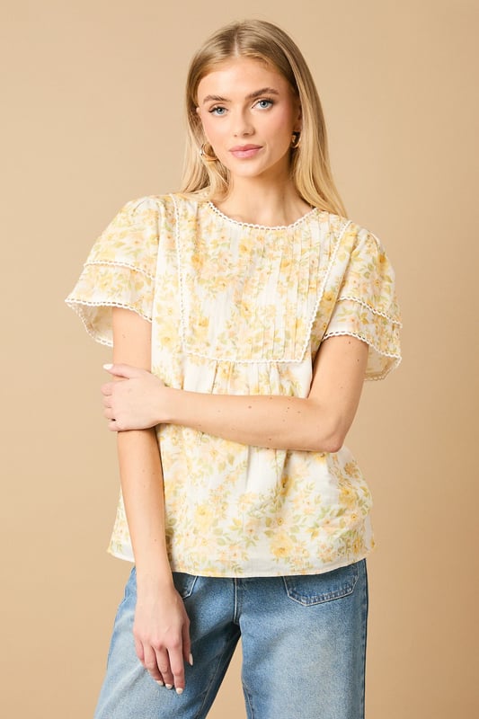 Charming crew neck blouse with delicate frill shoulder detail for a feminine touch
        Elegant pintuck detailing on the front bodice creates subtle texture and visual interest
        Dainty floral print throughout with a soft, romantic aesthetic
        Fluttery short sleeves with pretty trim detailing for added dimension
        Relaxed silhouette with a subtle empire waist for a flattering, comfortable fit
    
    This enchanting Oasis blouse combines classic femininity with contemporary styling. The delicate frill shoulders and pintuck detailing create a wonderfully romantic silhouette that's perfect for everyday wear. Style with relaxed denim jeans and flat sandals for casual weekend brunches, or pair with tailored trousers and ballet flats for a polished office look. The versatile design transitions beautifully from day to evening - simply swap your daytime accessories for statement earrings and a clutch bag for dinner with friends. The blouse's relaxed fit ensures all-day comfort whilst maintaining a put-together appearance, making it an ideal choice for family gatherings or casual meetups. This charming piece captures Oasis's signature feminine aesthetic whilst offering practical versatility for your everyday wardrobe.