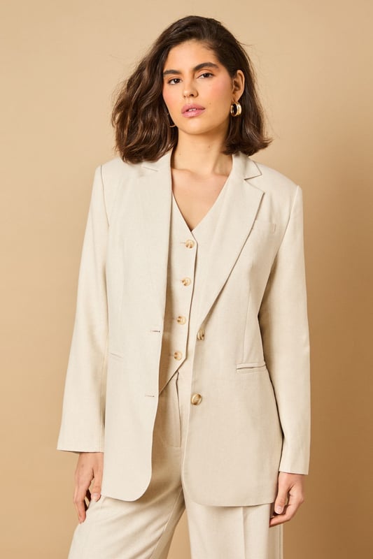 Oversized silhouette with relaxed shoulders for a contemporary, fashion-forward look
        Notched lapels and structured tailoring create a refined, elegant appearance
        Front button fastening with coordinating buttons for a cohesive finish
        Functional front pockets perfect for adding practicality to your formal ensemble
        Linen-look fabric offers a lightweight feel ideal for warmer weather occasions
    
    Make a statement with this beautifully crafted oversized blazer from Oasis. The relaxed fit creates a modern silhouette whilst maintaining a sophisticated edge that works brilliantly for both formal and casual settings. Style as seen with the matching wide-leg trousers for a coordinated suit that commands attention at summer weddings or garden parties. For everyday elegance, pair with slim-fit trousers and a simple camisole, finishing with delicate jewellery as shown on our model. The versatile nature of this blazer makes it perfect for layering during transitional seasons - wear open over a fitted dress for race day events or buttoned up with tailored shorts for a contemporary twist on occasion dressing. The clean lines and feminine cut embody Oasis' signature style whilst offering endless styling possibilities.