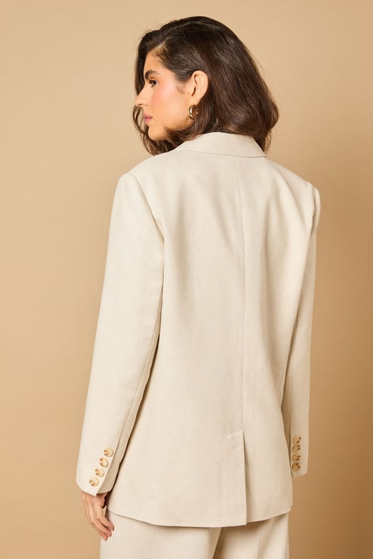 Oversized silhouette with relaxed shoulders for a contemporary, fashion-forward look
        Notched lapels and structured tailoring create a refined, elegant appearance
        Front button fastening with coordinating buttons for a cohesive finish
        Functional front pockets perfect for adding practicality to your formal ensemble
        Linen-look fabric offers a lightweight feel ideal for warmer weather occasions
    
    Make a statement with this beautifully crafted oversized blazer from Oasis. The relaxed fit creates a modern silhouette whilst maintaining a sophisticated edge that works brilliantly for both formal and casual settings. Style as seen with the matching wide-leg trousers for a coordinated suit that commands attention at summer weddings or garden parties. For everyday elegance, pair with slim-fit trousers and a simple camisole, finishing with delicate jewellery as shown on our model. The versatile nature of this blazer makes it perfect for layering during transitional seasons - wear open over a fitted dress for race day events or buttoned up with tailored shorts for a contemporary twist on occasion dressing. The clean lines and feminine cut embody Oasis' signature style whilst offering endless styling possibilities.