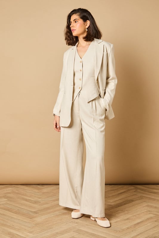 Oversized silhouette with relaxed shoulders for a contemporary, fashion-forward look
        Notched lapels and structured tailoring create a refined, elegant appearance
        Front button fastening with coordinating buttons for a cohesive finish
        Functional front pockets perfect for adding practicality to your formal ensemble
        Linen-look fabric offers a lightweight feel ideal for warmer weather occasions
    
    Make a statement with this beautifully crafted oversized blazer from Oasis. The relaxed fit creates a modern silhouette whilst maintaining a sophisticated edge that works brilliantly for both formal and casual settings. Style as seen with the matching wide-leg trousers for a coordinated suit that commands attention at summer weddings or garden parties. For everyday elegance, pair with slim-fit trousers and a simple camisole, finishing with delicate jewellery as shown on our model. The versatile nature of this blazer makes it perfect for layering during transitional seasons - wear open over a fitted dress for race day events or buttoned up with tailored shorts for a contemporary twist on occasion dressing. The clean lines and feminine cut embody Oasis' signature style whilst offering endless styling possibilities.
