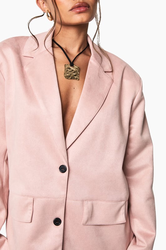 Single-breasted blazer with classic notched lapels for a timeless silhouette
        Soft faux suede texture that adds a tactile dimension to your outfit
        Two functional front pockets perfect for small essentials or styling
        Sleek two-button fastening for versatile styling options
        Regular fit design offering comfortable movement while maintaining structure
    
    This faux suede blazer brings effortless sophistication to your night-out wardrobe. The clean lines and structured shoulders create a flattering frame, whilst the soft-touch fabric adds a contemporary twist to traditional tailoring. Style as seen with a statement lace skirt for a captivating contrast of textures, or pair with slim-fit trousers and heels for drinks with the girls. For cooler evenings, layer over a fitted bodysuit or camisole top. Complete the look with statement jewellery and slim sunglasses for that perfect balance of polish and edge. This versatile piece transitions seamlessly from casual brunches to evening cocktails, making it an essential addition to your collection that works across seasons.