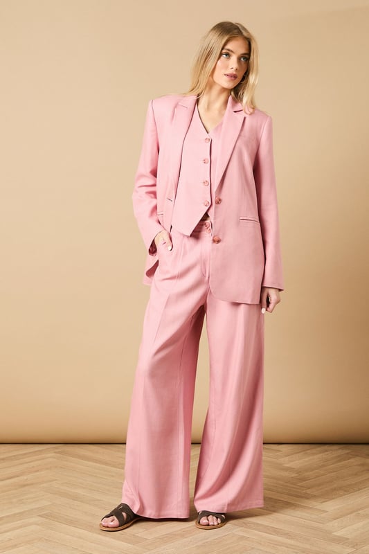 Oversized silhouette with relaxed shoulders for a contemporary, fashion-forward look
        Notched lapels and structured tailoring create a refined, elegant appearance
        Front button fastening with coordinating buttons for a cohesive finish
        Functional front pockets perfect for adding practicality to your formal ensemble
        Linen-look fabric offers a lightweight feel ideal for warmer weather occasions
    
    Make a statement with this beautifully crafted oversized blazer from Oasis. The relaxed fit creates a modern silhouette whilst maintaining a sophisticated edge that works brilliantly for both formal and casual settings. Style as seen with the matching wide-leg trousers for a coordinated suit that commands attention at summer weddings or garden parties. For everyday elegance, pair with slim-fit trousers and a simple camisole, finishing with delicate jewellery as shown on our model. The versatile nature of this blazer makes it perfect for layering during transitional seasons - wear open over a fitted dress for race day events or buttoned up with tailored shorts for a contemporary twist on occasion dressing. The clean lines and feminine cut embody Oasis' signature style whilst offering endless styling possibilities.
