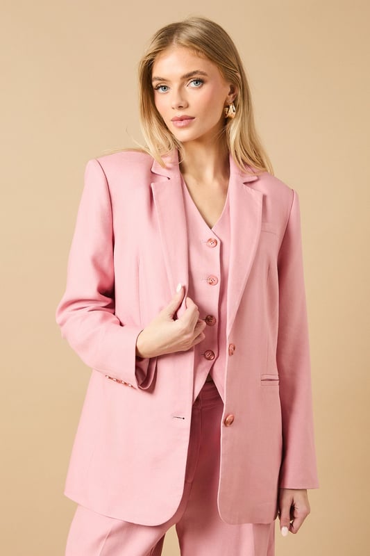 Oversized silhouette with relaxed shoulders for a contemporary, fashion-forward look
        Notched lapels and structured tailoring create a refined, elegant appearance
        Front button fastening with coordinating buttons for a cohesive finish
        Functional front pockets perfect for adding practicality to your formal ensemble
        Linen-look fabric offers a lightweight feel ideal for warmer weather occasions
    
    Make a statement with this beautifully crafted oversized blazer from Oasis. The relaxed fit creates a modern silhouette whilst maintaining a sophisticated edge that works brilliantly for both formal and casual settings. Style as seen with the matching wide-leg trousers for a coordinated suit that commands attention at summer weddings or garden parties. For everyday elegance, pair with slim-fit trousers and a simple camisole, finishing with delicate jewellery as shown on our model. The versatile nature of this blazer makes it perfect for layering during transitional seasons - wear open over a fitted dress for race day events or buttoned up with tailored shorts for a contemporary twist on occasion dressing. The clean lines and feminine cut embody Oasis' signature style whilst offering endless styling possibilities.